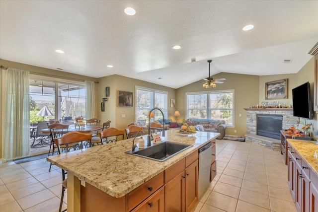 kitchen with stainless steel dishwasher, a sink, light tile patterned floors, and open floor plan