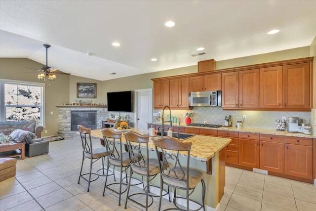 kitchen with appliances with stainless steel finishes, a sink, open floor plan, light tile patterned floors, and lofted ceiling