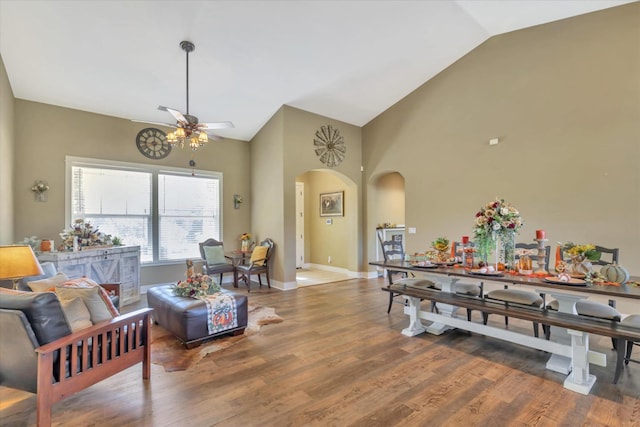 dining room featuring arched walkways, a ceiling fan, vaulted ceiling, and wood finished floors