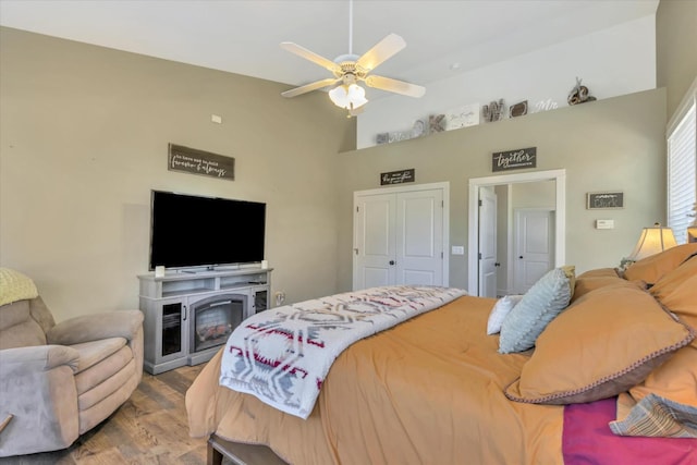 bedroom featuring a closet, ceiling fan, wood finished floors, and high vaulted ceiling