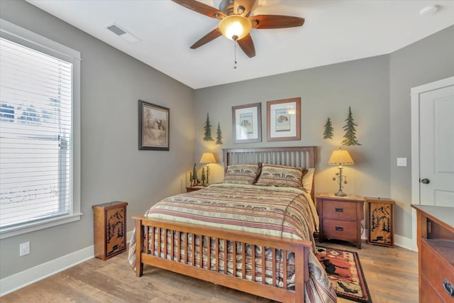 bedroom featuring baseboards, multiple windows, wood finished floors, and visible vents
