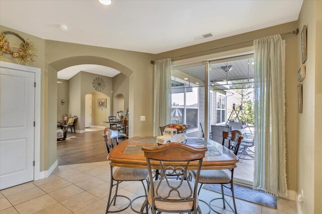 dining space featuring visible vents, arched walkways, baseboards, and light tile patterned floors