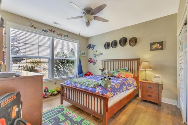 bedroom featuring visible vents, a ceiling fan, baseboards, and wood finished floors