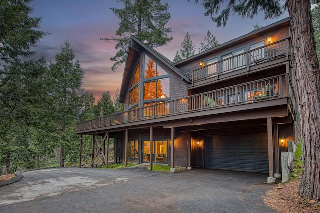 40596 Wild Iris Ln, Shaver Lake, CA 93664 - back of property at dusk with driveway, a balcony, and a garage