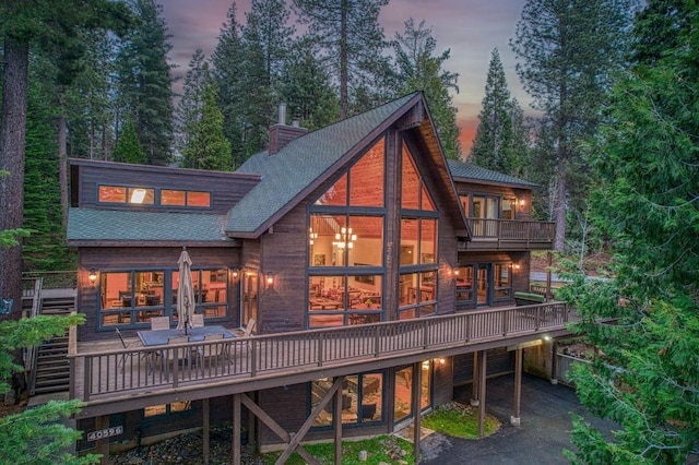 40596 Wild Iris Ln, Shaver Lake, CA 93664 - back of house at dusk with a chimney, a shingled roof, stairs, and a deck