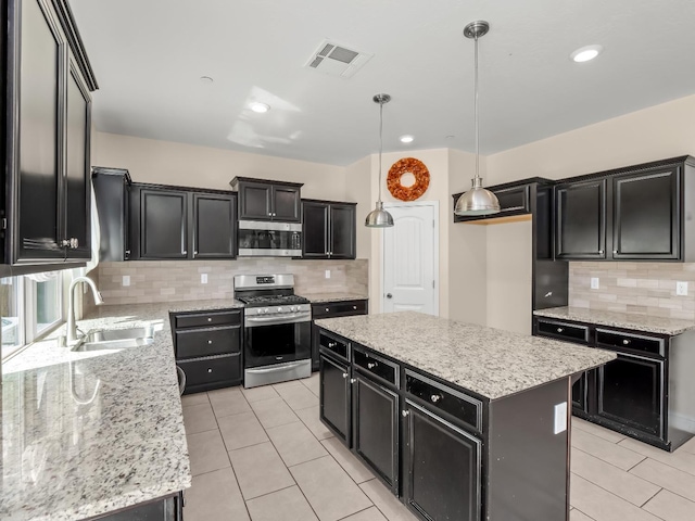 kitchen featuring visible vents, decorative backsplash, dark cabinetry, a sink, and stainless steel appliances
