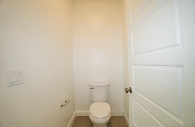 bathroom with baseboards, tile patterned flooring, and toilet