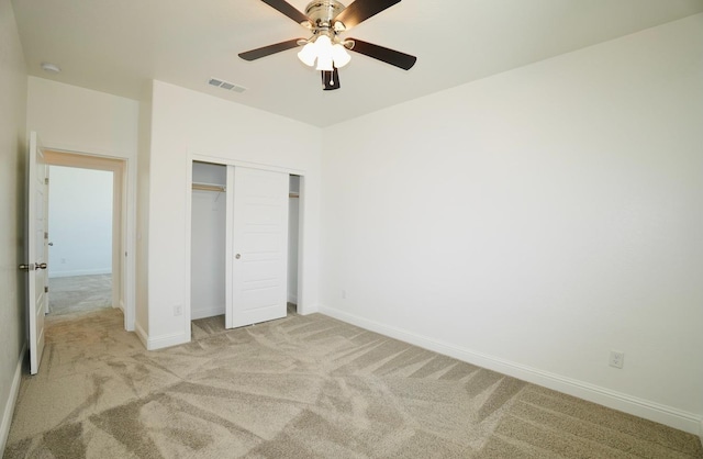 unfurnished bedroom with visible vents, a closet, light carpet, baseboards, and ceiling fan