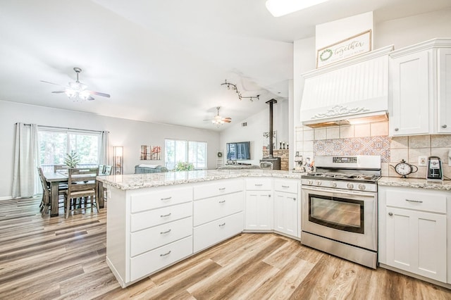 kitchen with stainless steel range with gas cooktop, a ceiling fan, light wood-type flooring, and a peninsula