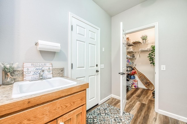 bathroom featuring baseboards, a sink, and wood finished floors