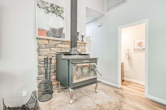 interior details featuring baseboards, a wood stove, wood finished floors, and visible vents