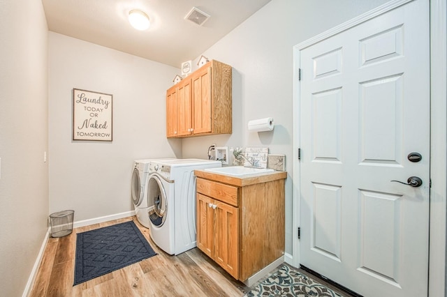 laundry area featuring washing machine and clothes dryer, visible vents, cabinet space, baseboards, and light wood finished floors