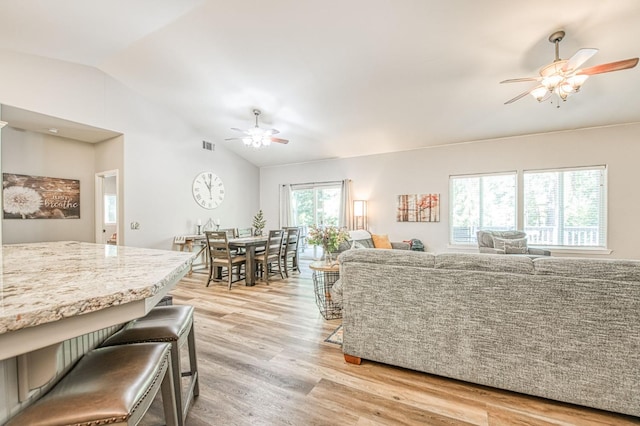 living room featuring ceiling fan, visible vents, lofted ceiling, and light wood-style floors