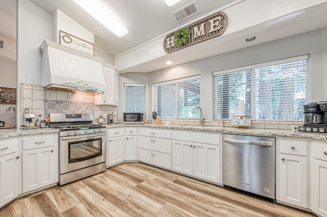 kitchen with visible vents, lofted ceiling, tasteful backsplash, a sink, and appliances with stainless steel finishes