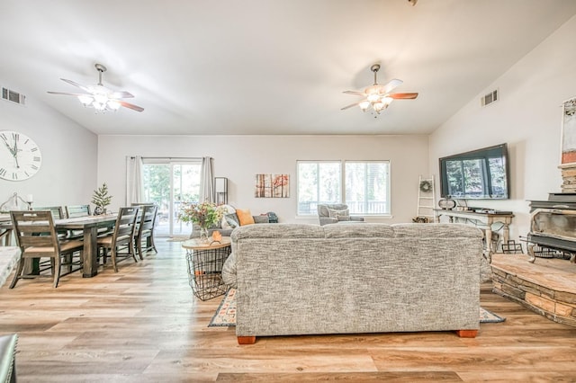 living room with a ceiling fan, vaulted ceiling, and visible vents