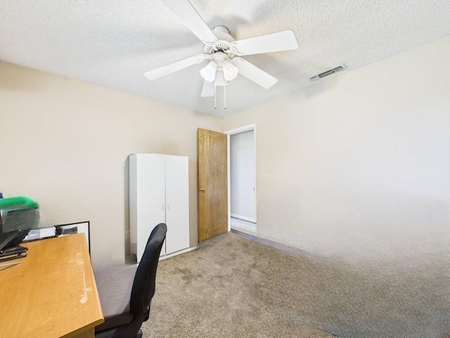 carpeted office space featuring a ceiling fan, a textured ceiling, and visible vents