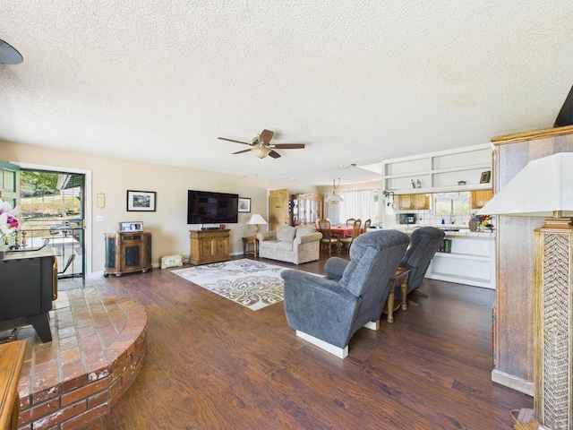 living room with a ceiling fan, a textured ceiling, and dark wood finished floors