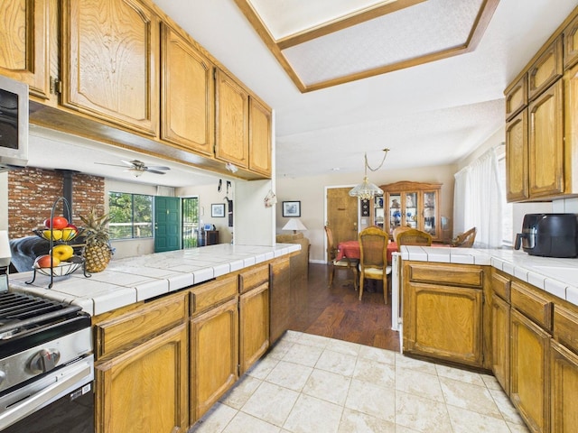 kitchen featuring a wood stove, appliances with stainless steel finishes, brown cabinets, and a peninsula