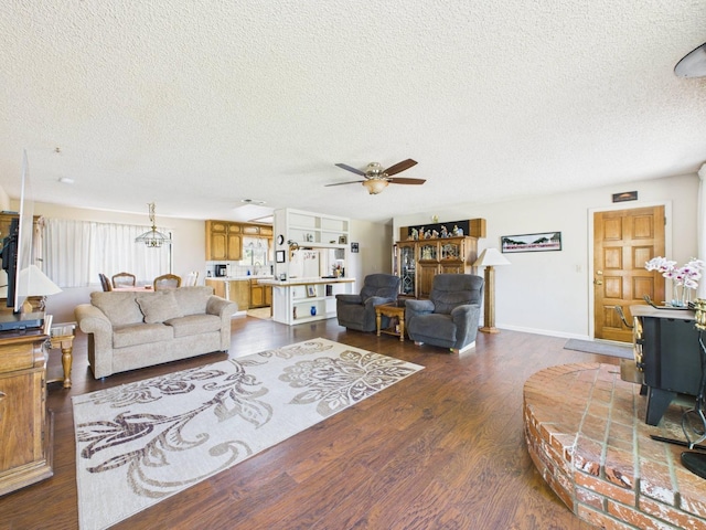 living area with a textured ceiling, dark wood finished floors, and ceiling fan with notable chandelier