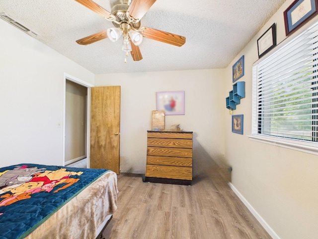 bedroom with visible vents, a ceiling fan, a textured ceiling, and wood finished floors