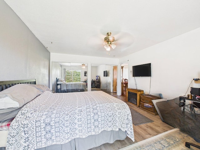 bedroom with ceiling fan, two closets, and wood finished floors