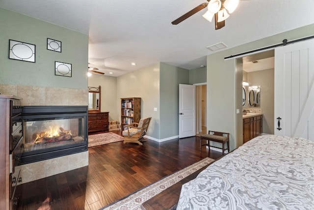 1389 Vineyard Pl, Hanford, CA 93230 - bedroom with a barn door, a tiled fireplace, baseboards, visible vents, and hardwood / wood-style flooring