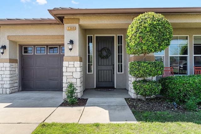 1389 Vineyard Pl, Hanford, CA 93230 - view of exterior entry with concrete driveway, stucco siding, stone siding, and a garage