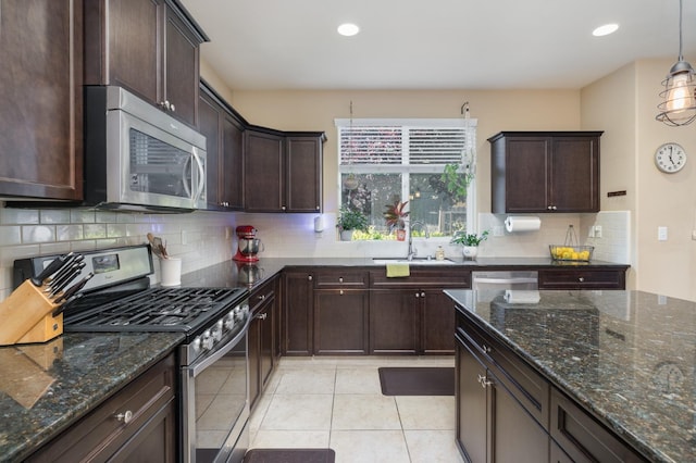 kitchen featuring a sink, dark stone counters, appliances with stainless steel finishes, and dark brown cabinetry