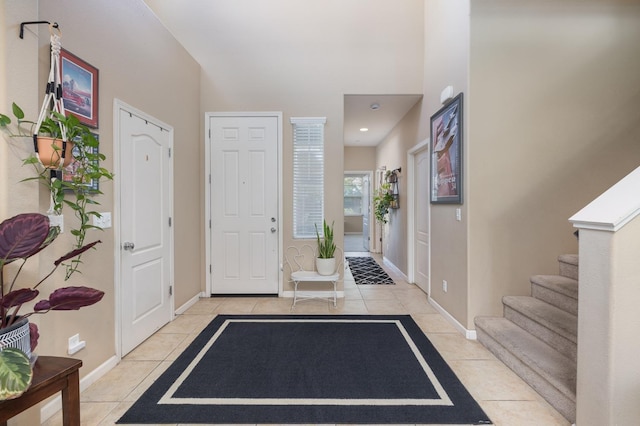 foyer with baseboards, light tile patterned floors, and stairway