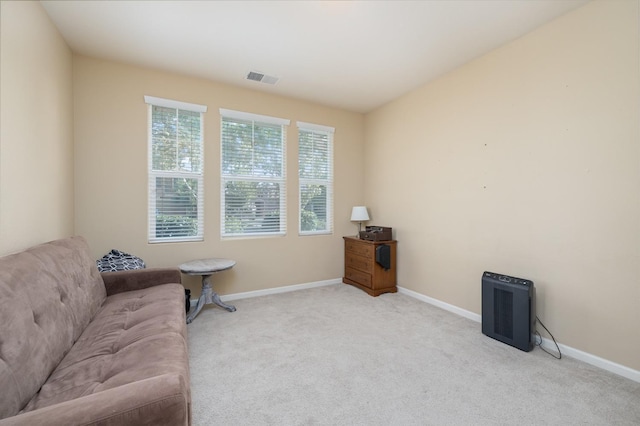 living area with baseboards, visible vents, and carpet