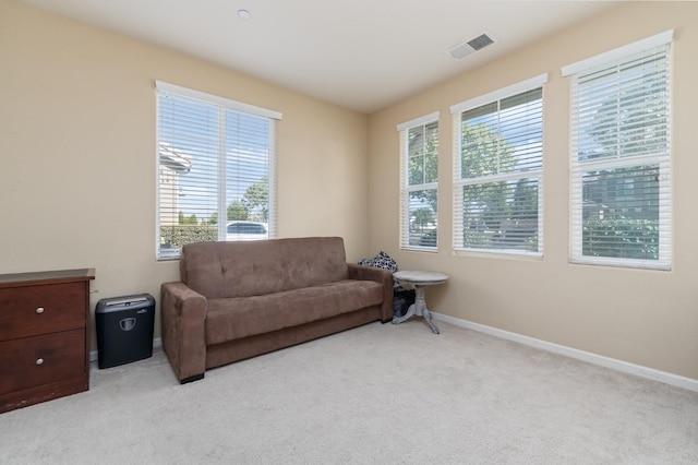 living area with baseboards, visible vents, light carpet, and a healthy amount of sunlight