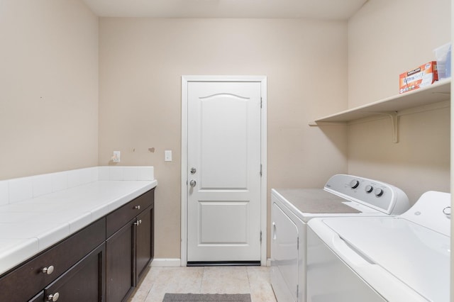 washroom with baseboards, light tile patterned flooring, cabinet space, and washer and dryer