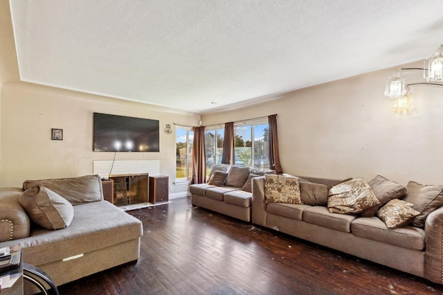living room featuring a fireplace with flush hearth, an inviting chandelier, dark wood finished floors, and a textured ceiling