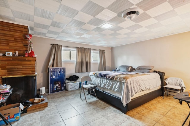 bedroom with a brick fireplace and light tile patterned floors