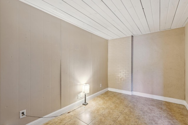 tiled empty room featuring baseboards and wooden ceiling
