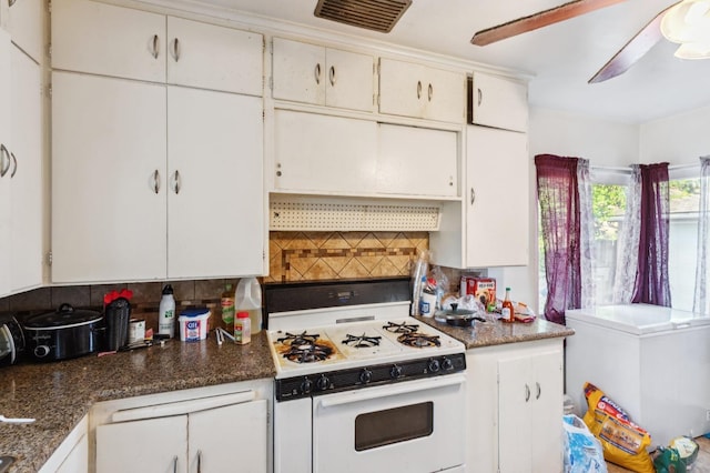 kitchen with white gas stove, visible vents, range hood, tasteful backsplash, and white cabinetry