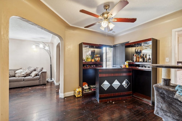 bar featuring ceiling fan, arched walkways, a dry bar, and hardwood / wood-style floors