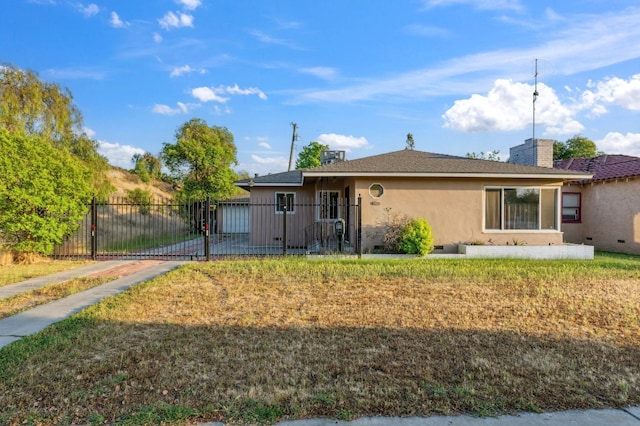 view of front of home with a chimney, a gate, fence private yard, a front lawn, and stucco siding