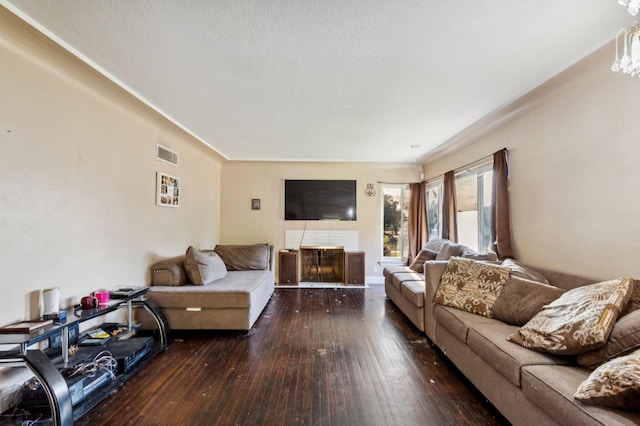 living area featuring wood-type flooring, a textured ceiling, visible vents, and a fireplace