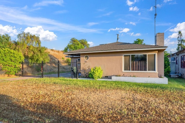 rear view of house with fence, a chimney, a lawn, and stucco siding