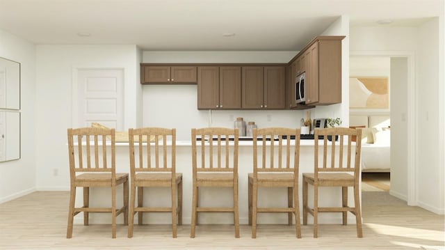 kitchen with light wood-style floors, baseboards, and stainless steel microwave