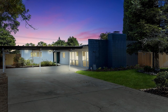 view of front of home featuring a yard, fence, driveway, and stucco siding