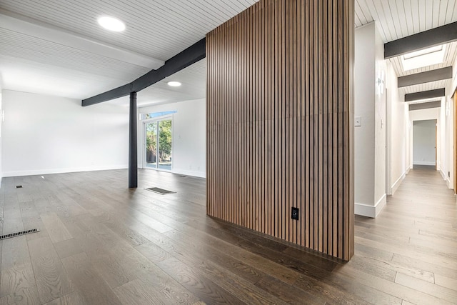 interior space featuring wood-type flooring, baseboards, and beamed ceiling