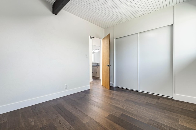 unfurnished bedroom with baseboards, a sink, dark wood-style floors, and a closet