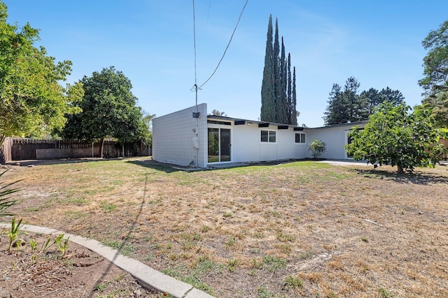 rear view of property featuring a yard and fence