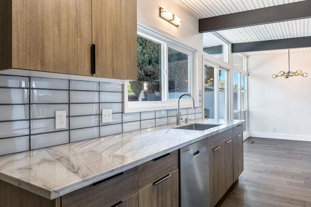 kitchen with modern cabinets, stainless steel dishwasher, a sink, baseboards, and beamed ceiling