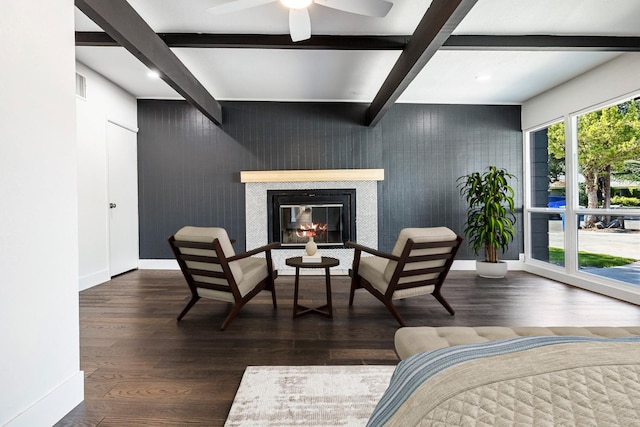 sitting room with ceiling fan, beam ceiling, wood finished floors, baseboards, and a glass covered fireplace
