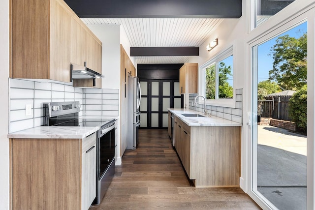 kitchen with decorative backsplash, dark wood-style flooring, wall chimney exhaust hood, a sink, and appliances with stainless steel finishes