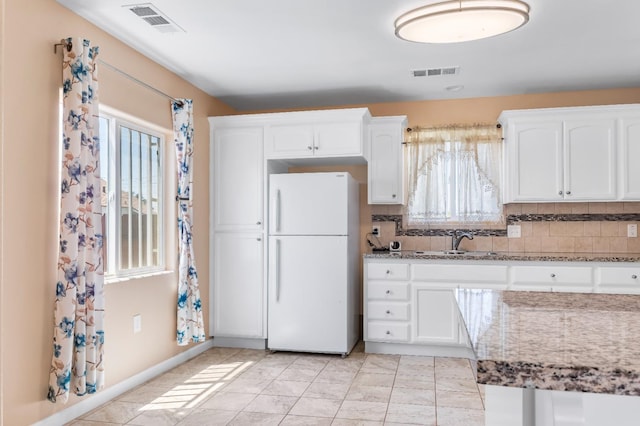 kitchen featuring a sink, a healthy amount of sunlight, freestanding refrigerator, and visible vents