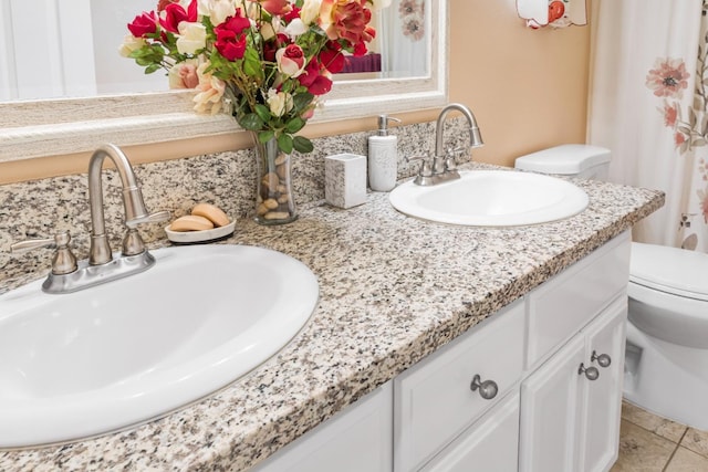 full bath with double vanity, toilet, and a sink
